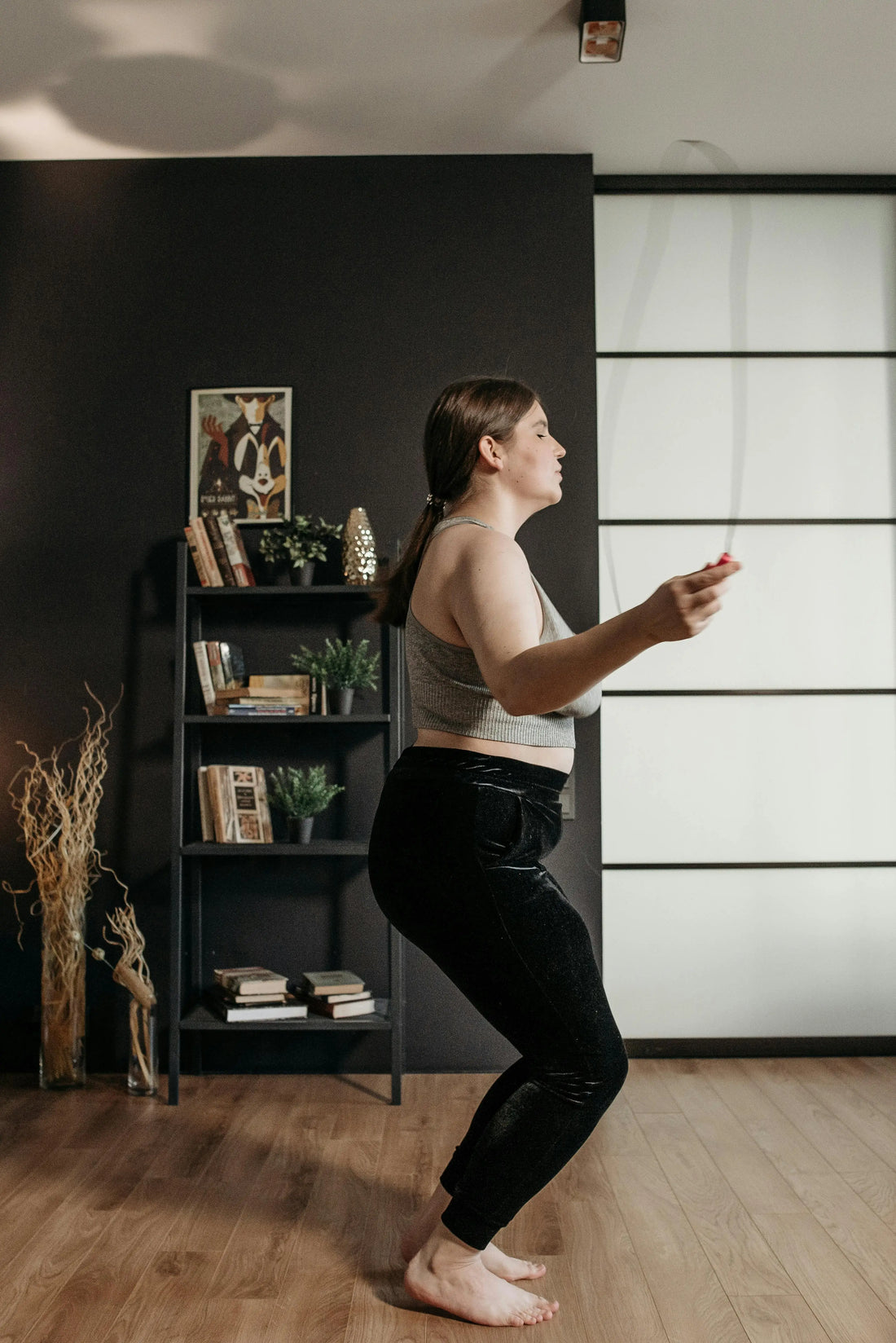 Woman jumping rope indoors in her living room, exercising for fitness and health.