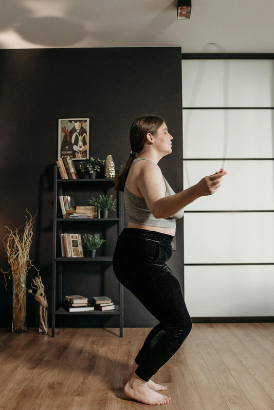Woman jumping rope indoors in her living room, exercising for fitness and health.