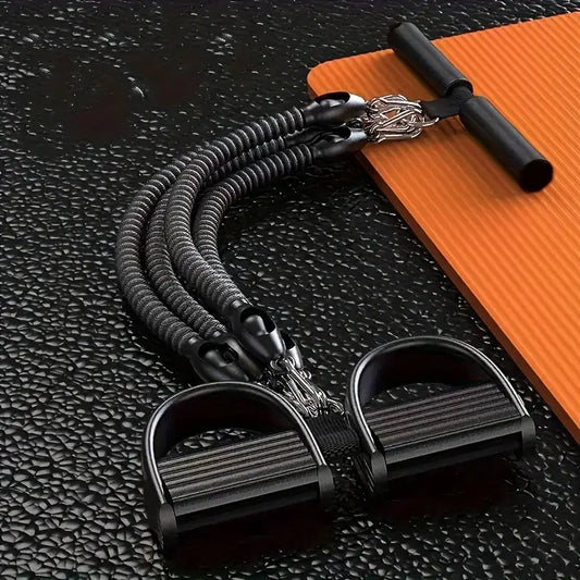 Durable resistance bands with foam pedal puller and handle bar, placed on textured black gym flooring next to an orange yoga mat for full body strength training and home workouts