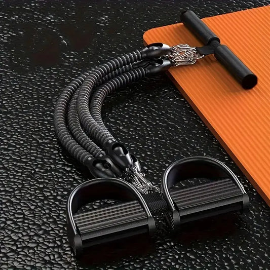 Durable resistance bands with foam pedal puller and handle bar, placed on textured black gym flooring next to an orange yoga mat for full body strength training and home workouts